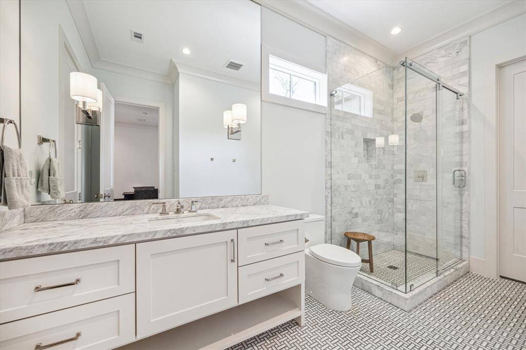 Secondary bathroom with frameless glass shower, natural light.