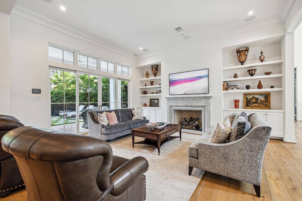 Family room with woodburning fireplace, custom cabinetry, surround sound, is an inviting space to relax with family and friends.  A summer kitchen, patio, pool and backyard are all right through the beautiful glass doors.  The European Oak hardwood floors that run throughout the home bring additional warmth to the space.