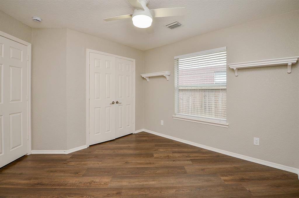 A charming secondary bedroom will please both family visiting guests, with what looks like good sized closet and nice wall shelving.