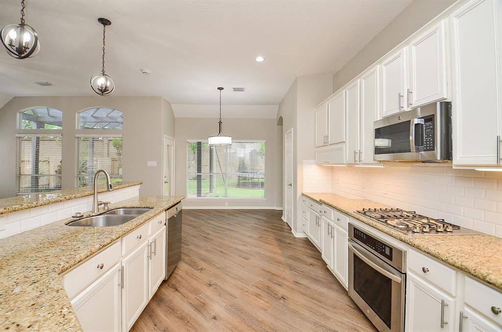 Wide floor paths and sleek placement of appliances are just two bonuses in this dream chef's kitchen. White cabinetry goes on forever, up and down; matched with streamlined granite counters and pale tile backspalsh everywhere you land!