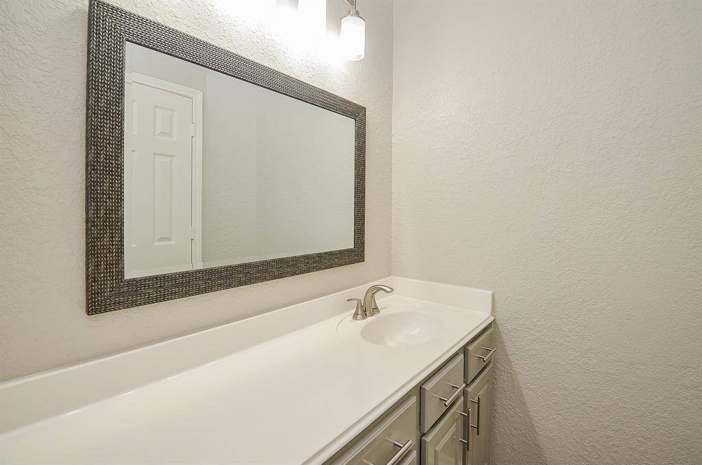 An artistic framed mirror sits above this sink console in a secondary bath.