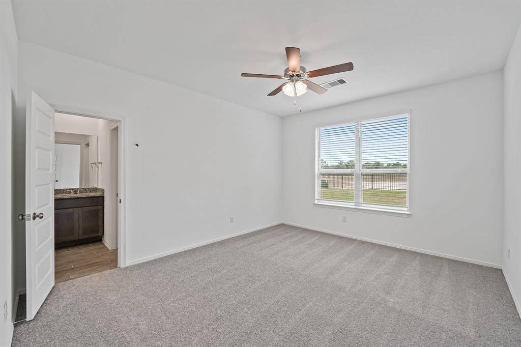 A look into this Prestigious Primary Suite that is accompanied with Plush Carpeting, Ceiling Fan, and Oversized Windows that feature Lakefront views!