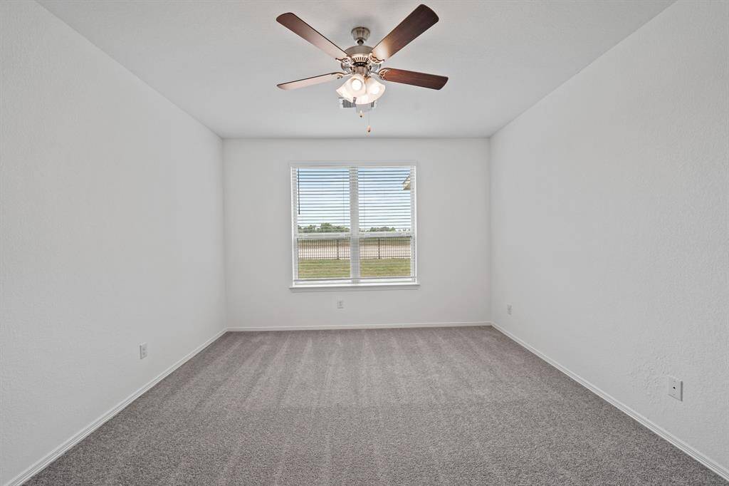 An additional view of the Stunning Primary Bedroom that is accompanied with ceiling fan and easy access to Primary Bath Oasis and serene lake view.