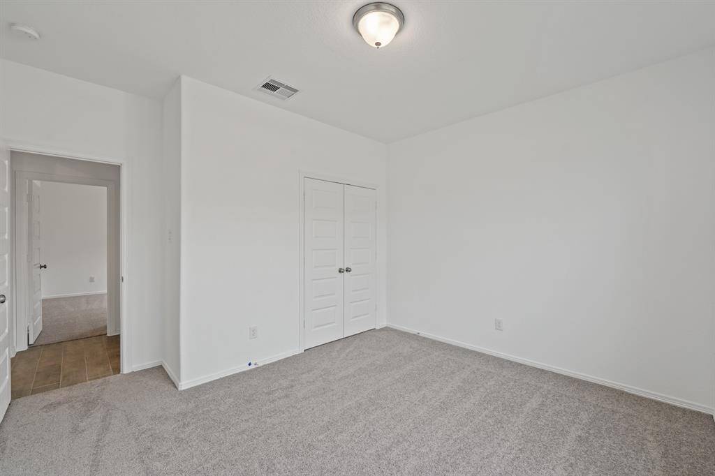 A look into another Splendid Secondary Bedroom that offer plush carpeting, natural lighting from window, and easy access to the other living spaces within the home.