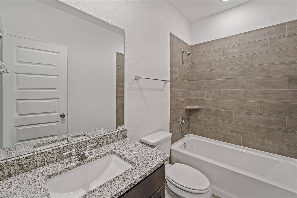 Full Secondary Bathroom features extended mirror, sleek countertop and handsome dark cabinetry, as well as shower and bathtub combination with tile surround.