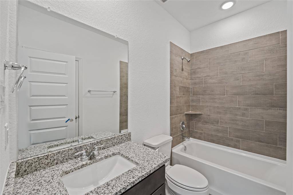 Stylish secondary bathroom featuring a sleek countertop, modern fixtures, and a tiled shower/tub combo with built-in ledge for convenience.
