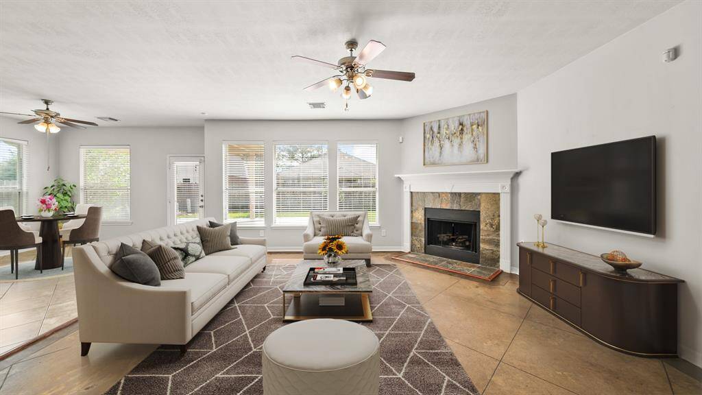 Virtually Staged: This stunning living room features tile floors, gorgeous fireplace, a ceiling fan, and tons of natural light thanks to the large windows.