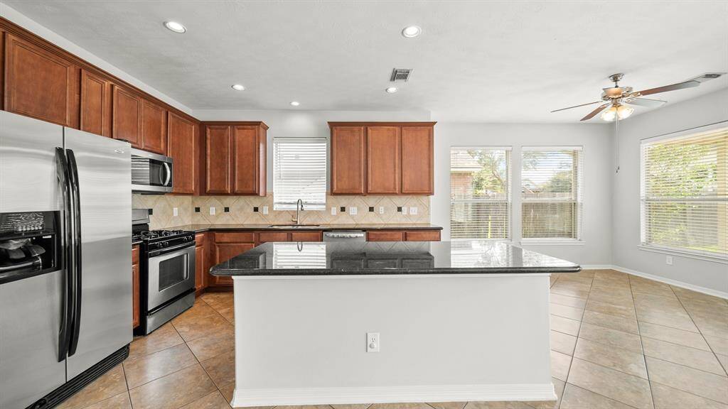 Tile floors, and recessed lighting complete this kitchen-breakfast nook space.