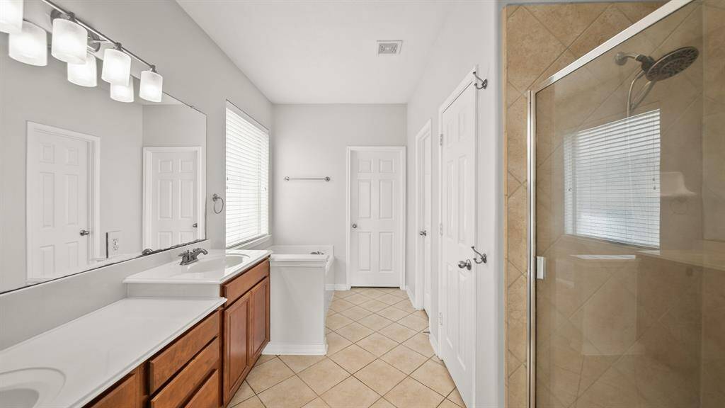 Welcome to your very own retreat! This en-suite bathroom features double sinks, a large mirror, granite countertops, a glass enclosed walk-in shower, and tile floors.