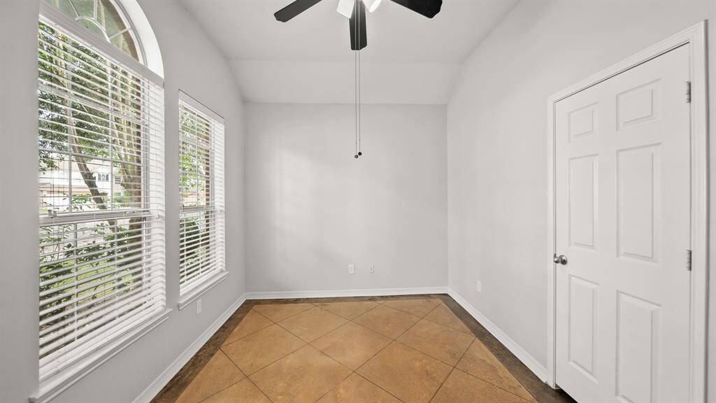 Nestled quietly in the front of the house is secondary bedroom with tile floors, a built-in closet, a ceiling fan, and windows with privacy blinds.