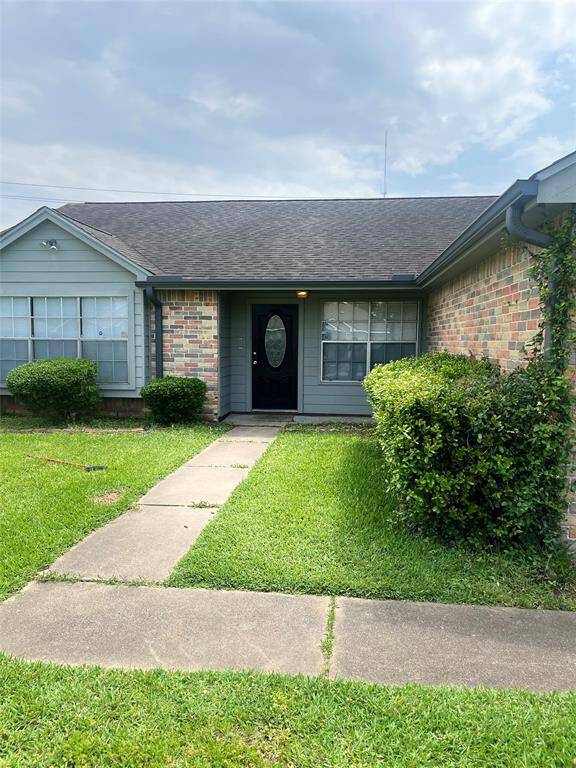 This photo shows a charming single-story home with a brick exterior and a covered entryway. The front yard is well-maintained with lush green grass and neatly trimmed bushes, providing a welcoming first impression.