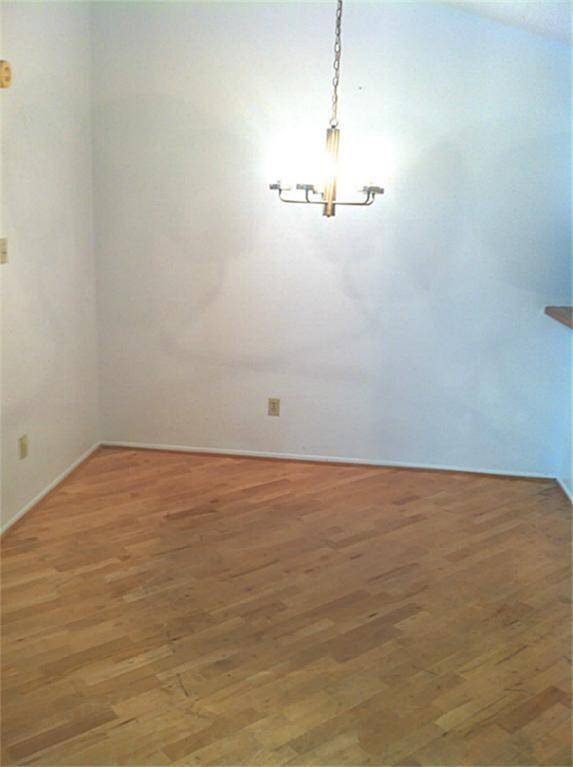 This photo shows a small dining area with light wood flooring and a simple overhead light fixture. The walls are painted white, giving the space a clean, bright look.