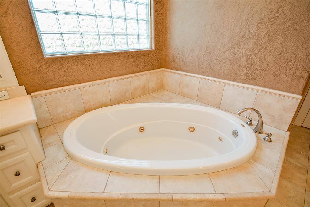 Cozy, art-deco like windows above your primary, jetted Hollywood tub brings light and privacy as you luxuriate!