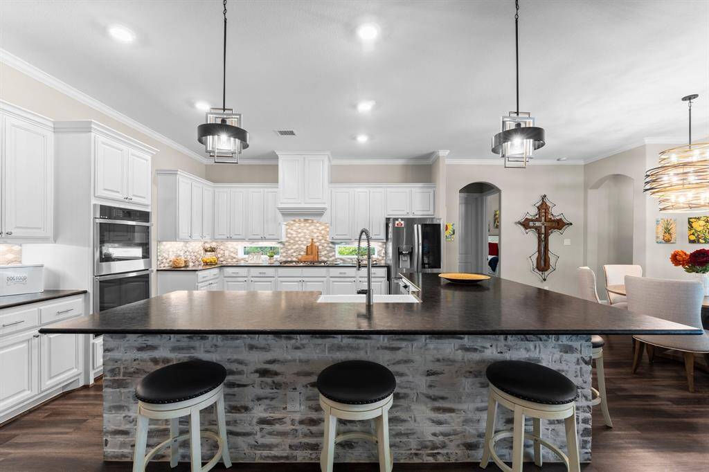 Topped with gorgeous leathered granite, this expansive island comfortably seats six, creating an inviting, open space perfect for effortless entertaining and unforgettable gatherings.