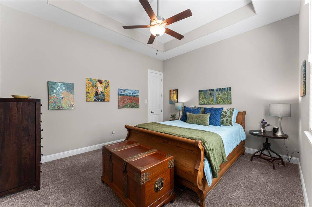 Featuring a generous walk-in closet, elegant tray ceiling with a ceiling fan for optimal comfort, and a private en-suite bathroom, this spacious secondary bedroom offers a tranquil retreat.