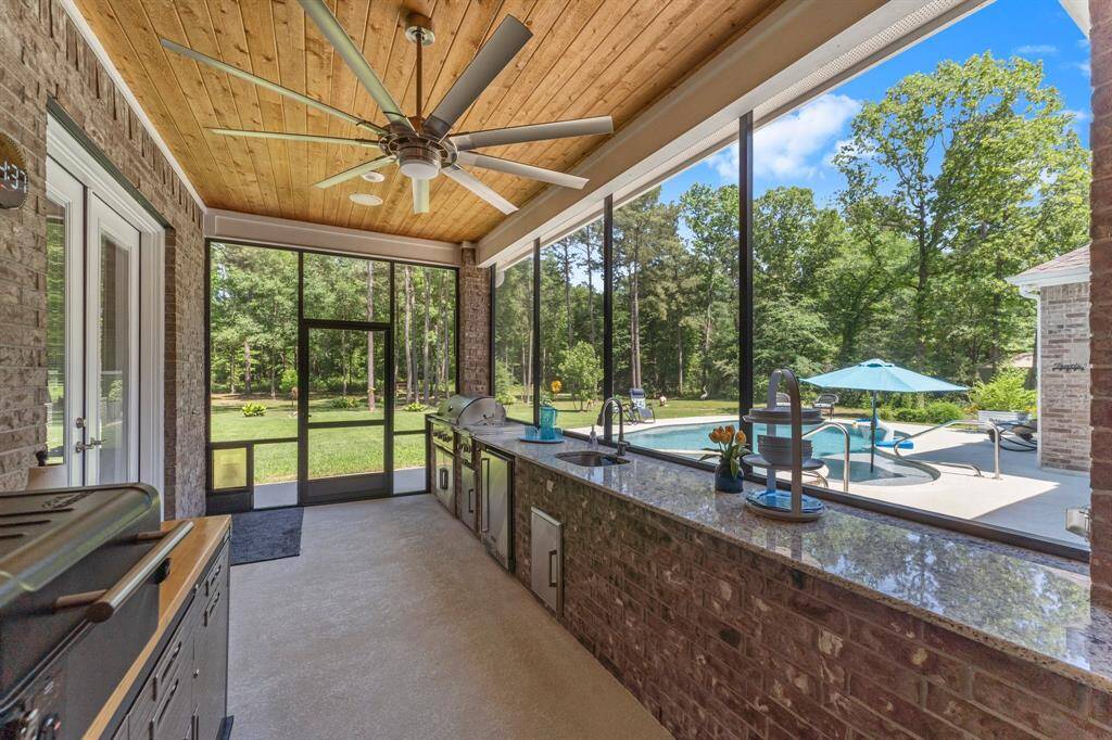 The screened back porch also includes this extensive outdoor kitchen with gas grill, double side burner, refrigerator, sink with hot and cold water, granite countertops and oversized fan. Double doors lead to the media room.