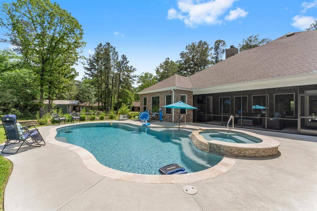 The pool with travertine coping and a view of the back of the home and screened porch.