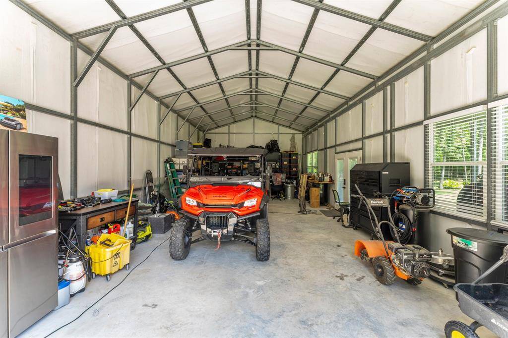 The spacious workshop offers 200-Amp Electrical Service, a 10’x10’ Roll-Up Door, and Double French Side Doors leading to the covered porch.