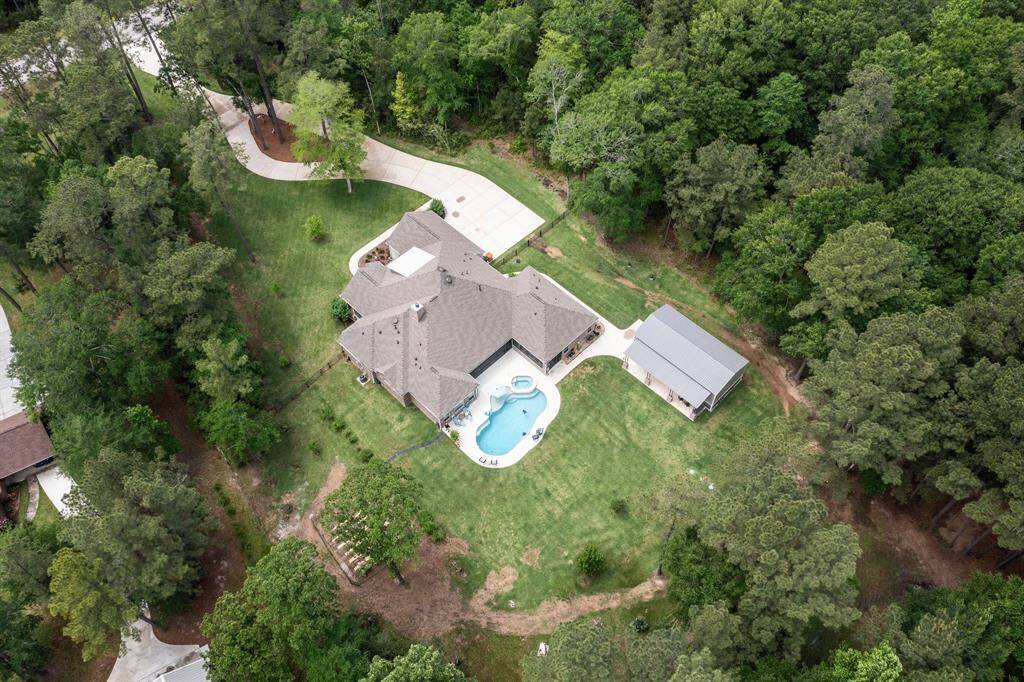 A bird's eye view of this 3 acre property with long circular driveway, oversized motor court, gorgeous custom home, pool and spa, metal workshop/building, vegetable garden and woods behind home.