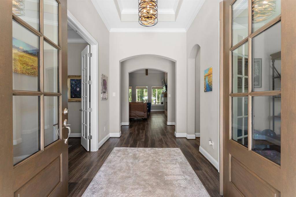The double doors lead you into a beautiful entry with elegant light fixture, architectural details including archways and tray ceiling.