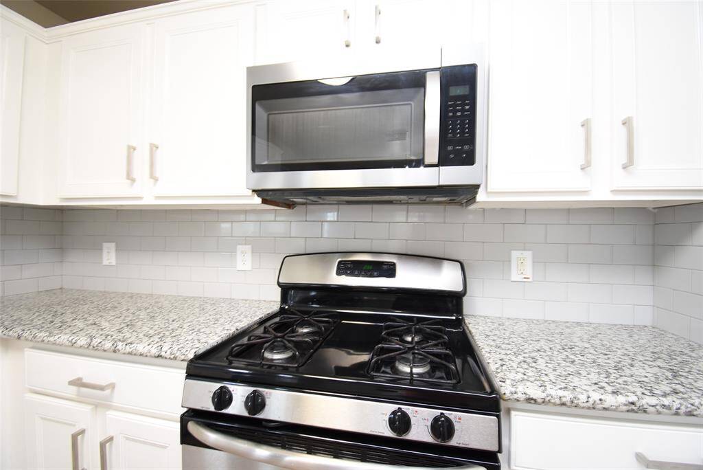 This kitchen is designed for both style and efficiency, featuring sleek stainless-steel appliances, a gas range, and a built-in microwave. The granite countertops and crisp white cabinetry complete the contemporary look. A perfect space for everyday living!