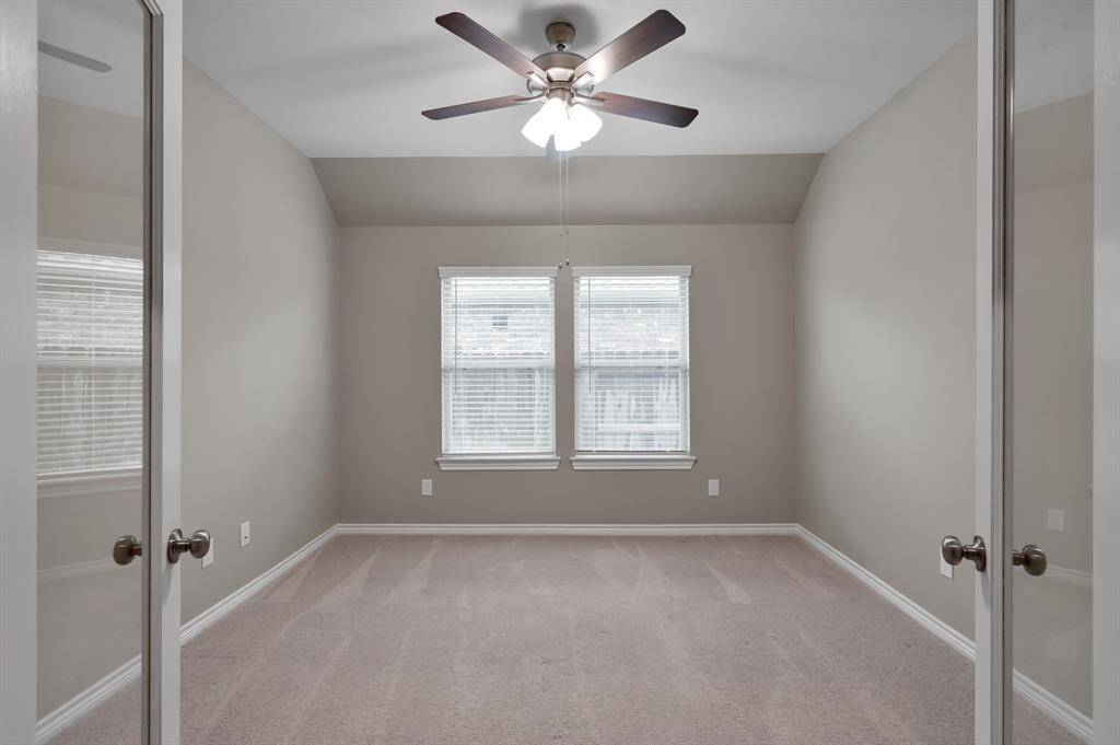 Double french doors enclose a large home office with plenty of natural light.