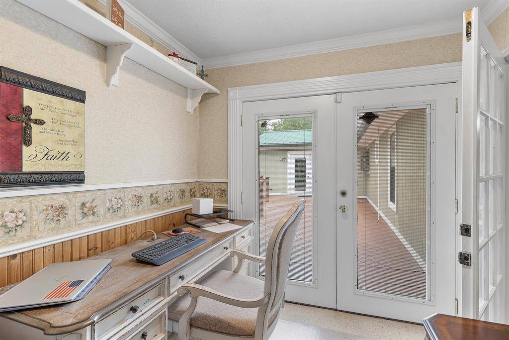 A cozy home office off the primary bedroom features French doors leading to a deck, providing natural light and outdoor access. Ideal for a peaceful and productive workspace.