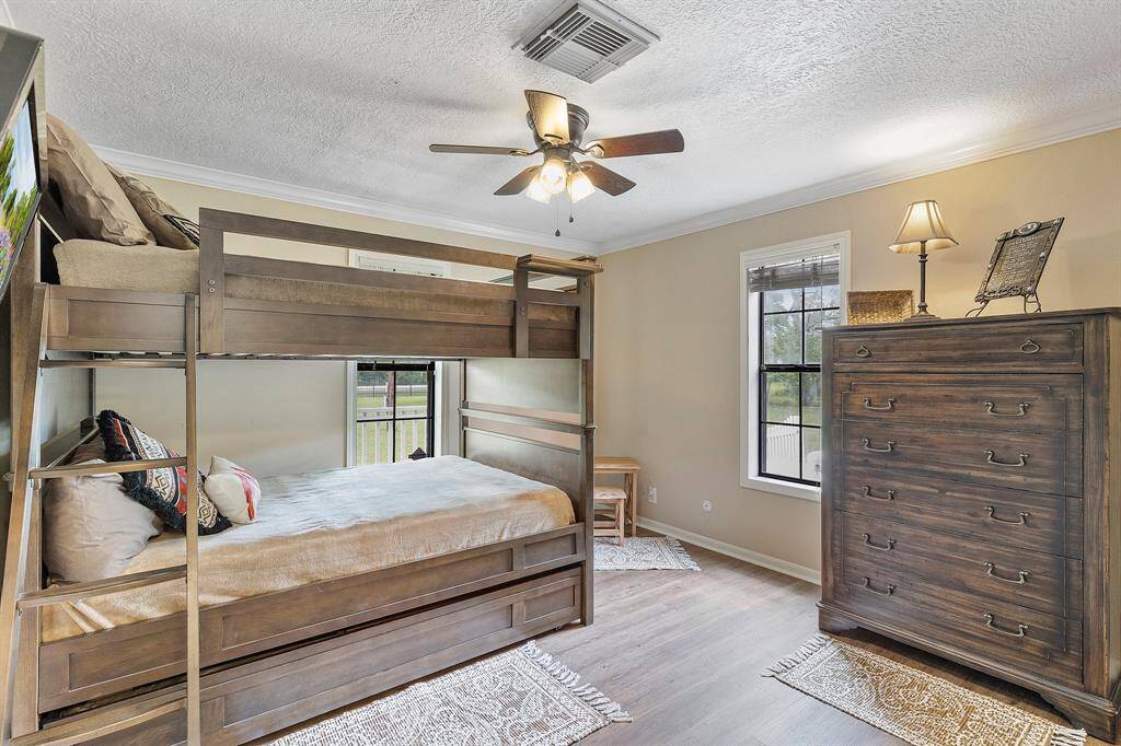 Another cozy secondary bedroom featuring two windows providing natural light. Ceiling fan enhances comfort, and the room offers a warm, inviting atmosphere with neutral walls and wood flooring.