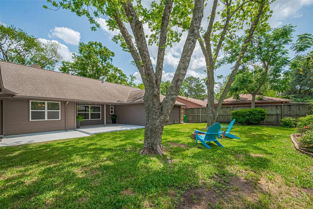 Another view of the expansive backyard, featuring landscaping and plenty of space for outdoor entertaining or relaxing in the shade.