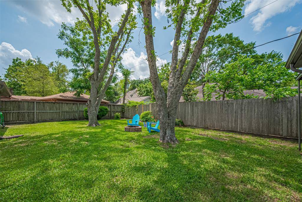 Another view of the expansive backyard, featuring lush landscaping and plenty of space for outdoor entertaining or relaxing in the shade.