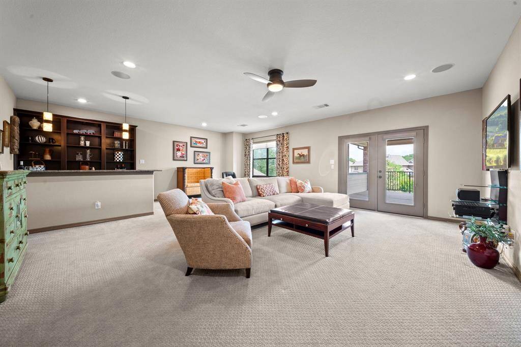 Just off the landing is this enormous gameroom with built-in cabinets, a bar with built in sink and french doors to the upstairs patio