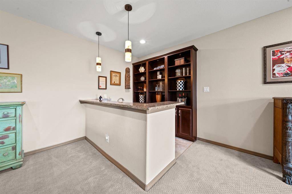 The gameroom bar with granite counters and pendent lighting