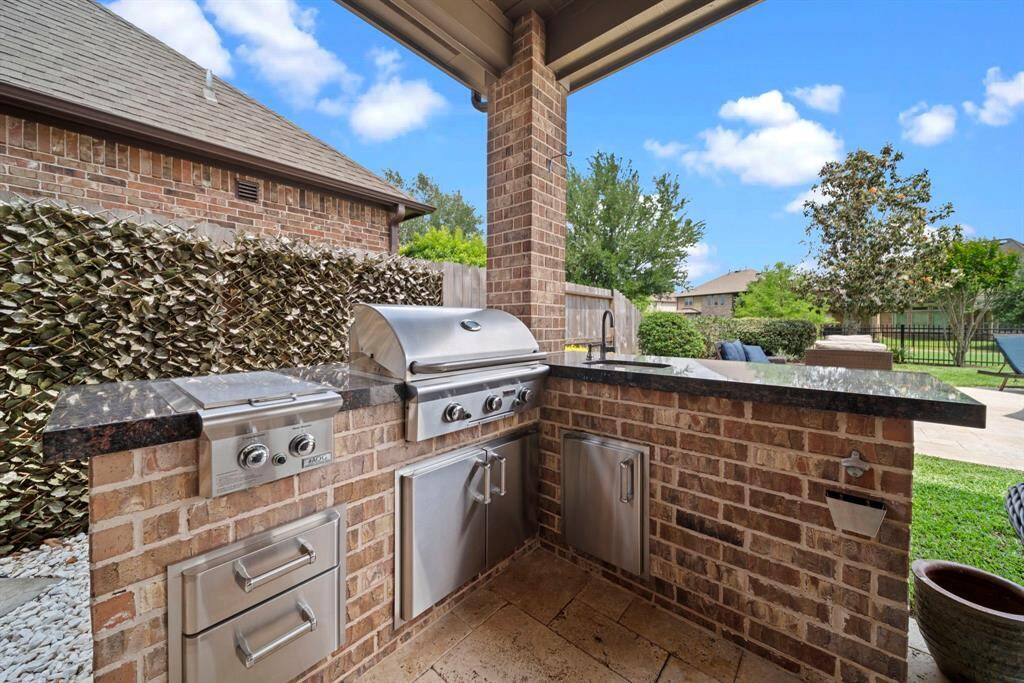 The outdoor kitchen with grill, sink, warming drawers and storage all while enjoying the view of the pool and greenspace