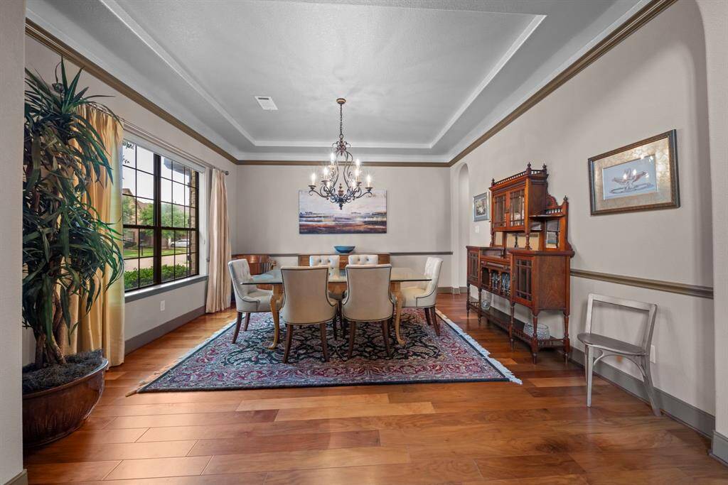 The forma dining room with tray ceiling and custom paint also has plantation shutters and wood laminate flooring