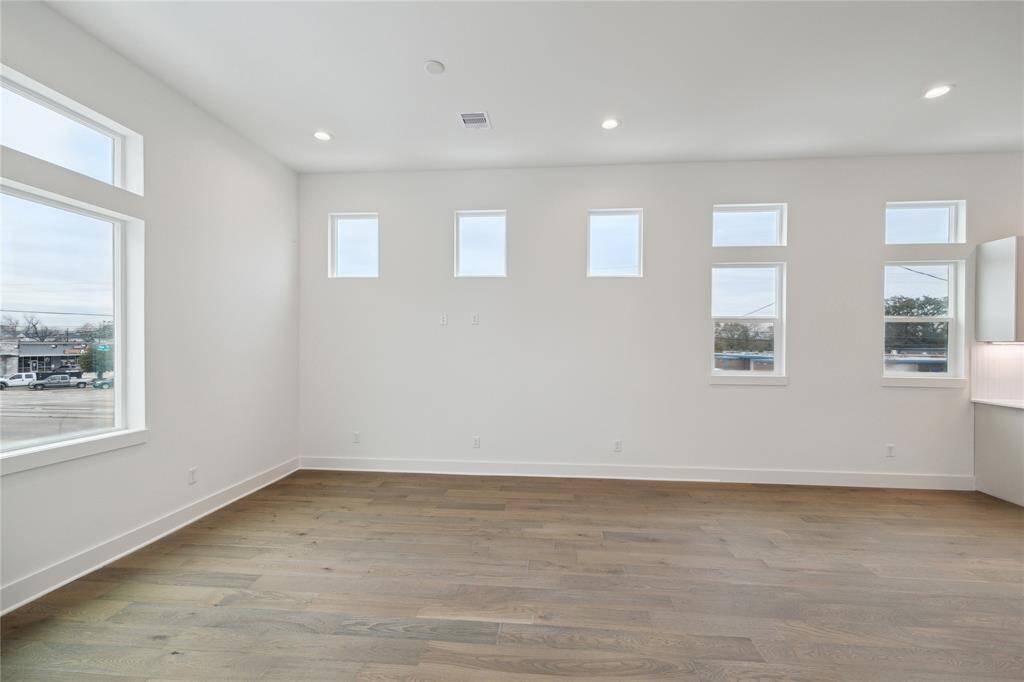 Bright and spacious living area featuring large windows and elegant hardwood floors, perfect for relaxing and entertaining.