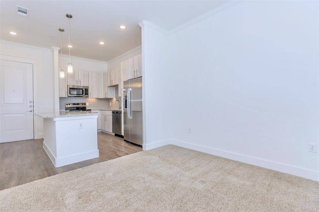 Kitchen with island and breakfast bar, modern white wood grain cabinetry, stainless steel appliances, and under cabinet lighting