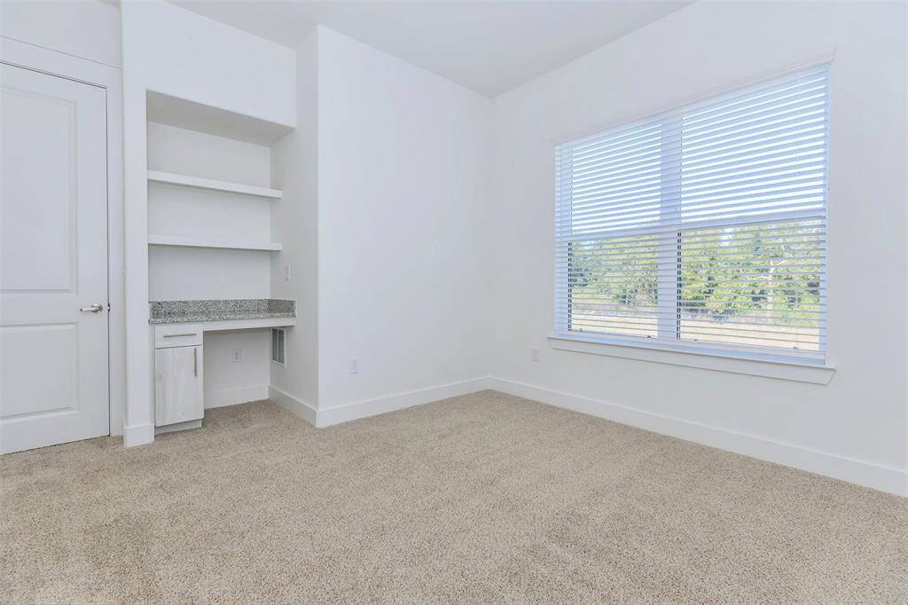 Spacious primary bedroom with built-in desk and natural light