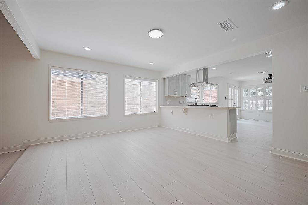 The formal dining space is open to the kitchen and living area with recessed lighting and a wall of windows.