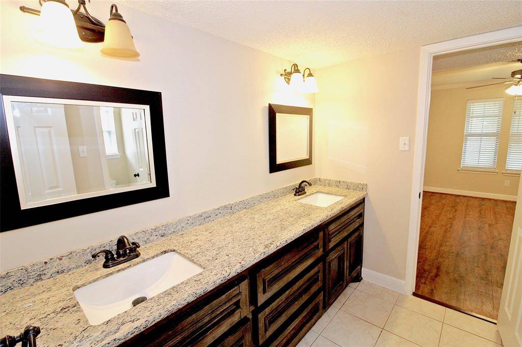 Updated guest bathroom with dual sinks and granite countertops.