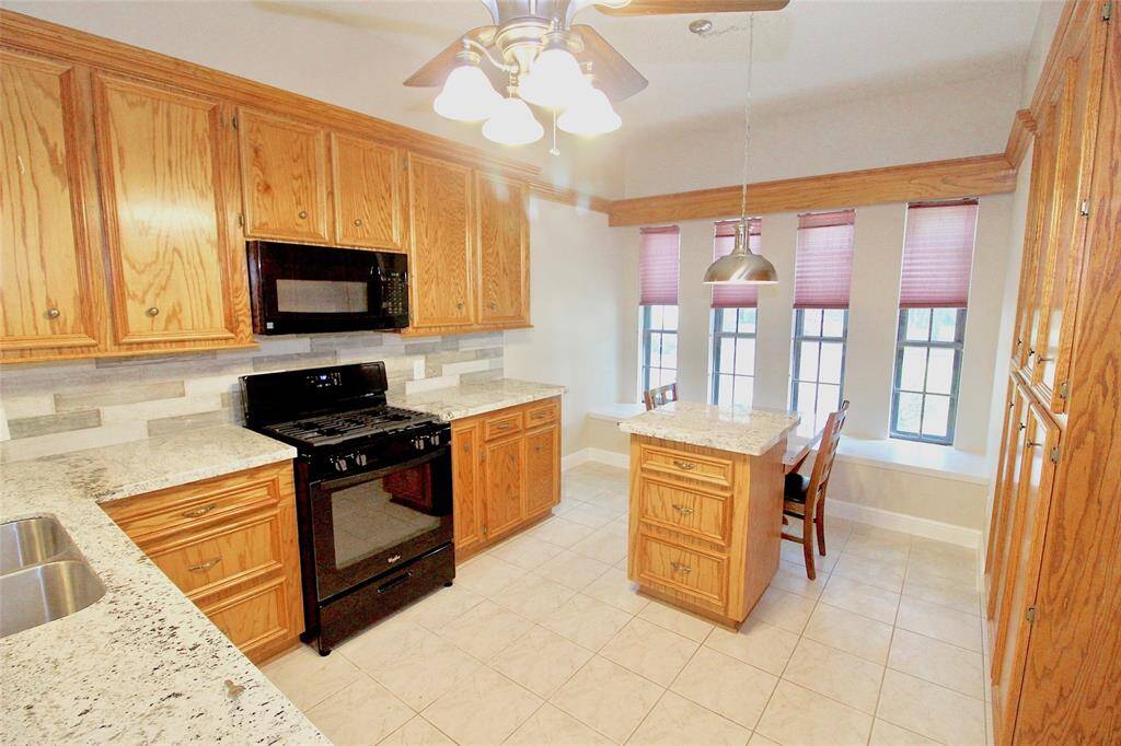 Different angle view of the kitchen with custom breakfast table & gas range.