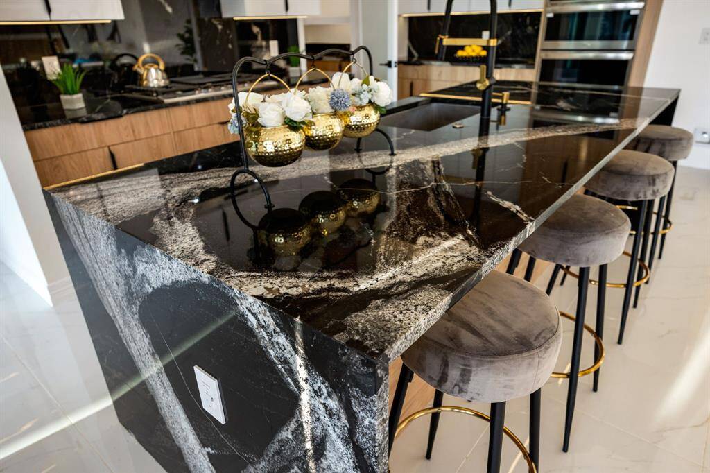 Experience luxury at its finest with this striking kitchen centerpiece—a waterfall-edge island crafted from dramatic, high-gloss black granite featuring intricate natural veining. The rich, polished stone extends seamlessly to the floor, creating a bold, sculptural statement. Complemented by sleek fixtures and exquisite craftsmanship, this space epitomizes modern elegance and attention to detail.