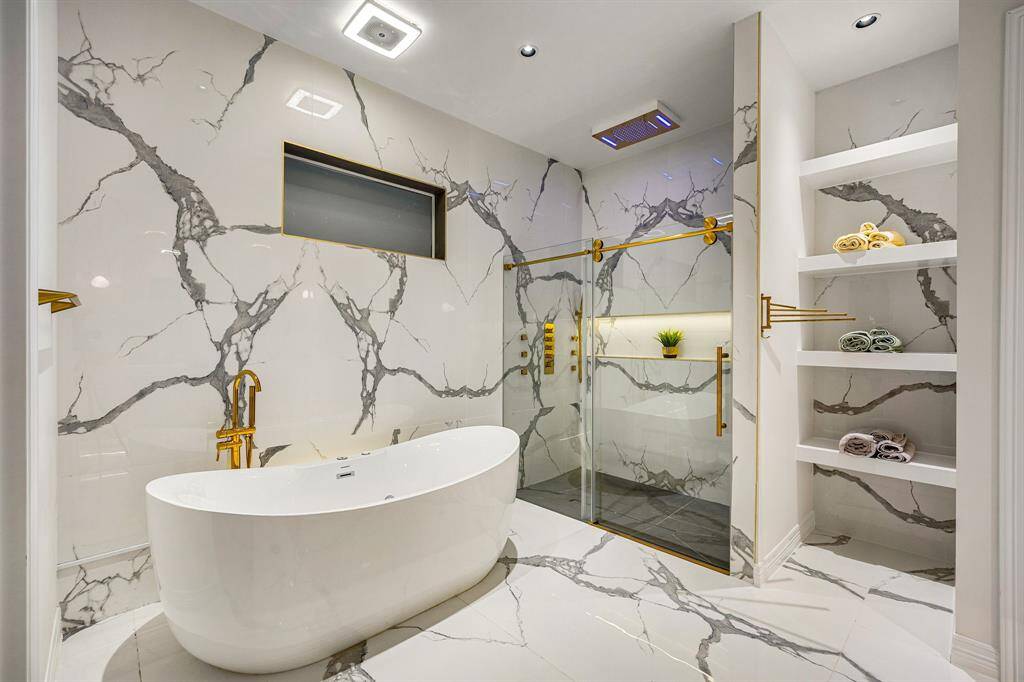 ChatGPT said:Immerse yourself in ultimate luxury with this breathtaking en suite bathroom, showcasing a sculptural freestanding soaking tub, oversized rainfall shower with LED lighting, and striking book-matched marble surfaces throughout. Gold accents and built-in shelving elevate the space, creating a spa-inspired sanctuary designed for pure indulgence.