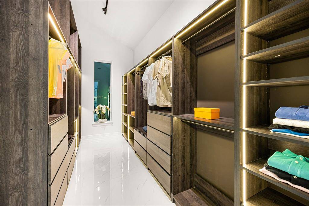 Step into a boutique-style walk-in closet designed for both elegance and functionality. Custom wood cabinetry with soft-close drawers, abundant shelving, and integrated LED lighting provide a luxurious backdrop for organizing your wardrobe in style. A sleek, modern layout makes this space as beautiful as it is practical.