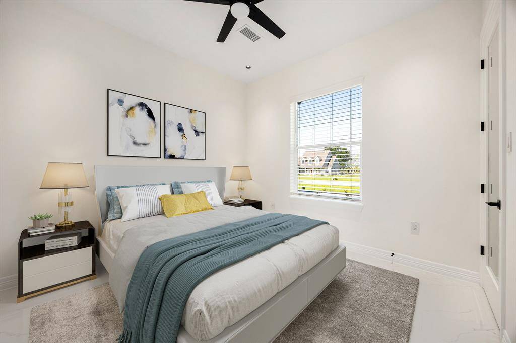 This bright and inviting secondary bedroom features a large window that fills the space with natural light, complemented by a soothing neutral palette and modern finishes. A ceiling fan, plush carpeting, and tasteful decor make this room both comfortable and stylish—perfect for guests or family.
