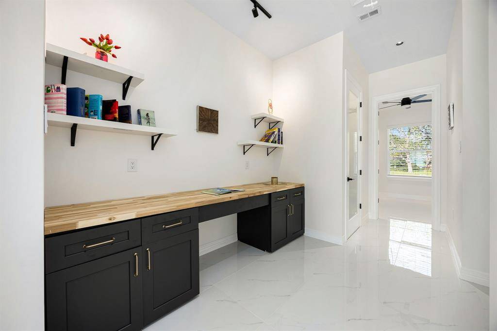 This versatile bonus space is ideal for a home office or dedicated homework area, featuring a built-in desk with ample storage, floating shelves for organization, and sleek finishes. Natural light and a clean, modern design make it both functional and inviting.