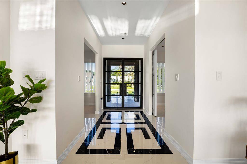 Step into elegance with this stunning entryway featuring sleek black-framed glass doors and striking custom tile inlay flooring—setting the tone for a home that blends modern design with timeless sophistication.