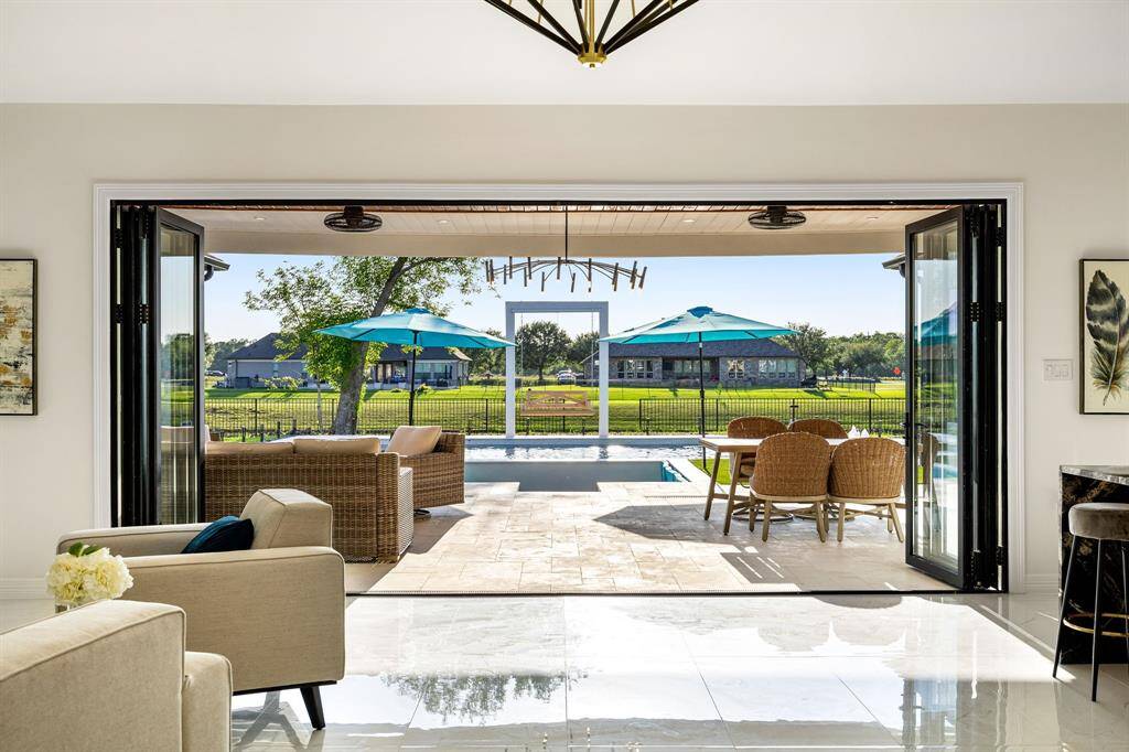 Experience true indoor-outdoor living with this beautifully designed space that opens up to a spacious covered patio, sparkling pool, and serene views of lush greenery beyond the fence line. Perfect for entertaining or relaxing in total tranquility.