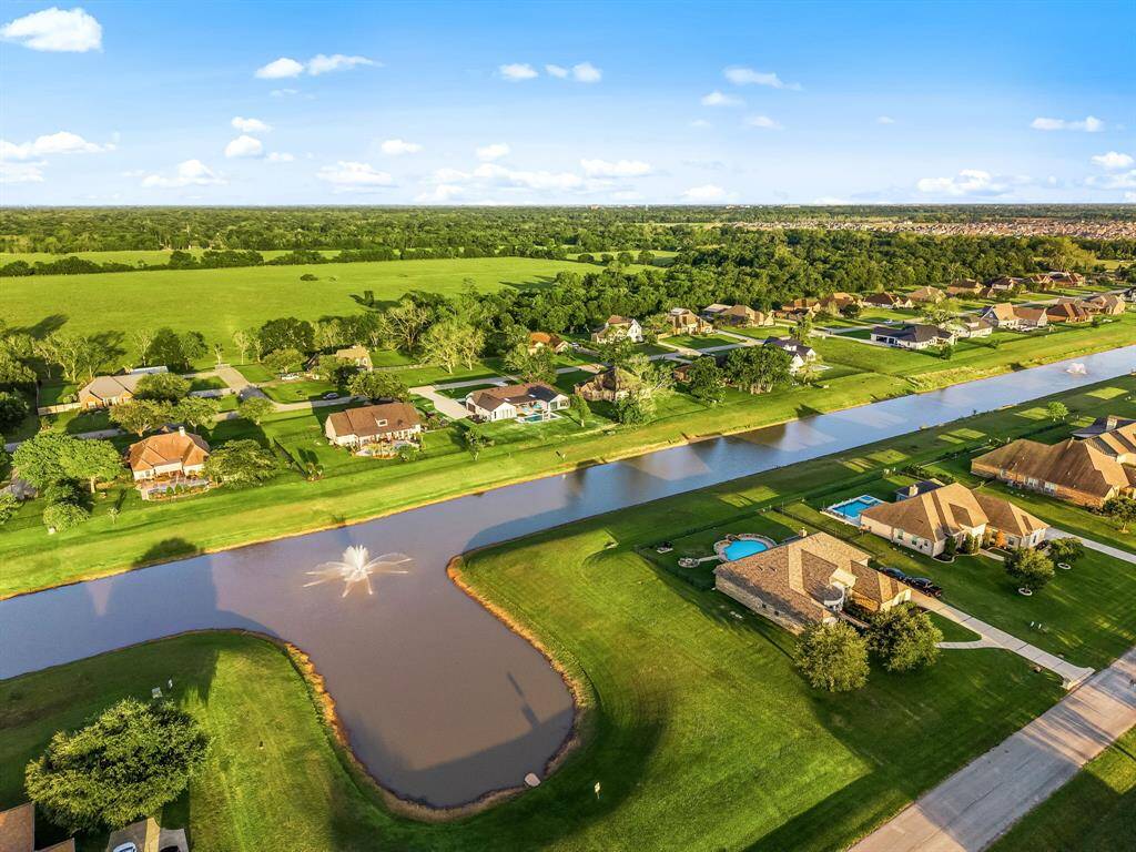 Experience peaceful living in a beautifully landscaped community with expansive green spaces and a scenic canal running through the neighborhood. This aerial view showcases the serene atmosphere, private waterfront lots, and a harmonious blend of nature and luxury living.