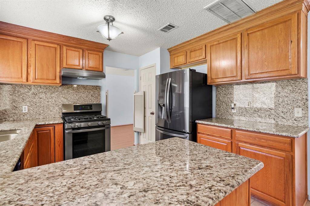 Recently installed kitchen appliances. Granite countertops paired with a full-height backsplash offer durability and easy maintenance.