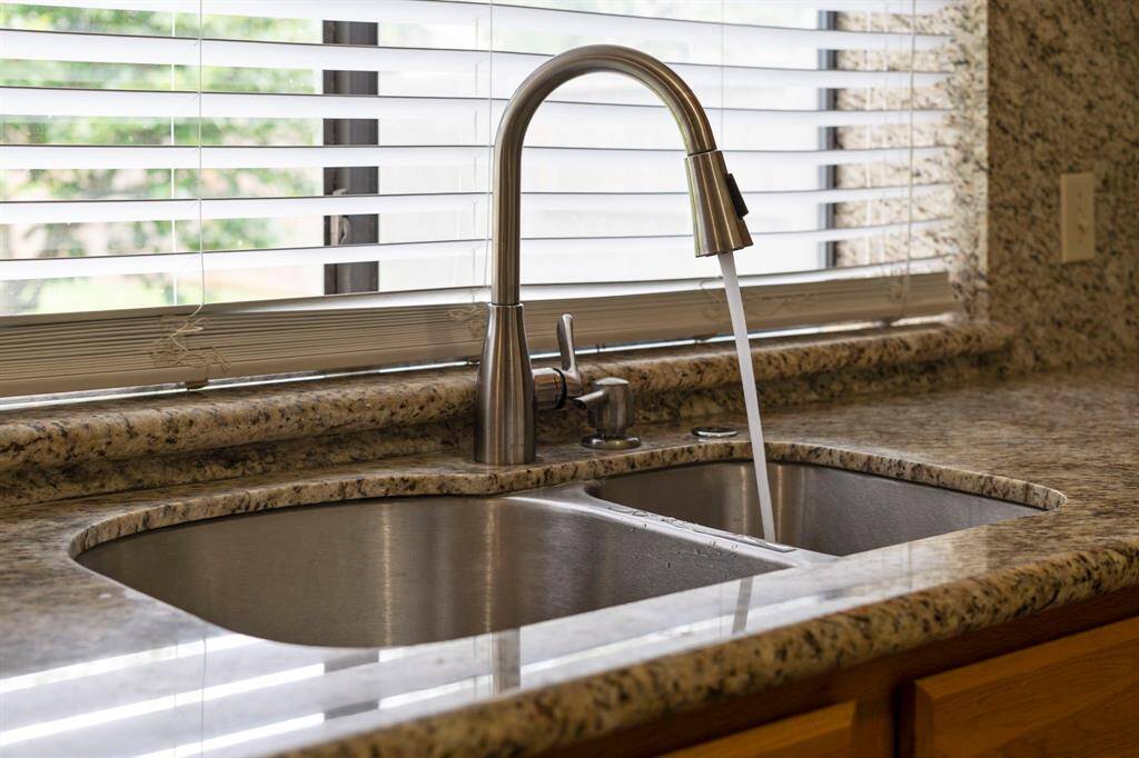 A stainless steel double sink is complemented by a NEW (just installed) modern gooseneck pull-down faucet.